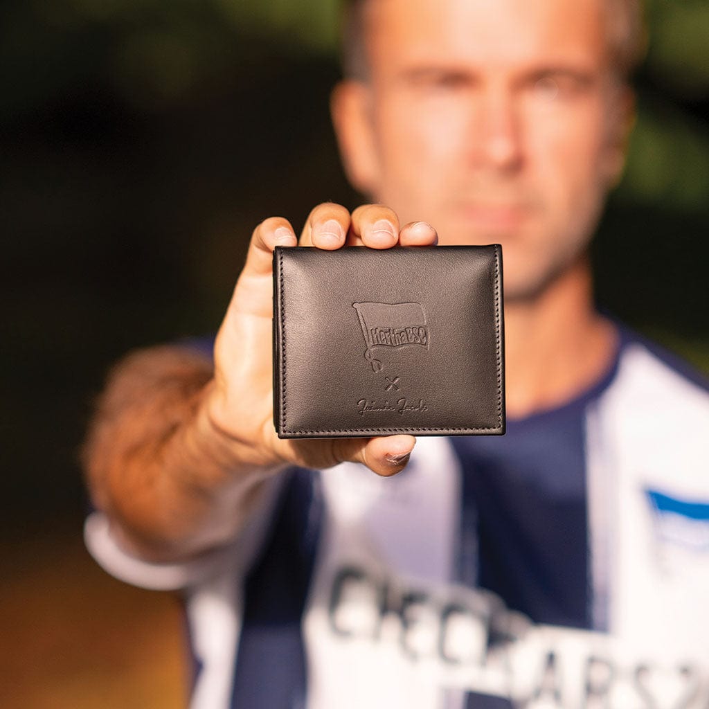 fan hält flap boy geldbeutel von jaimie jacobs mit dem hertha bsc logo in die kamera